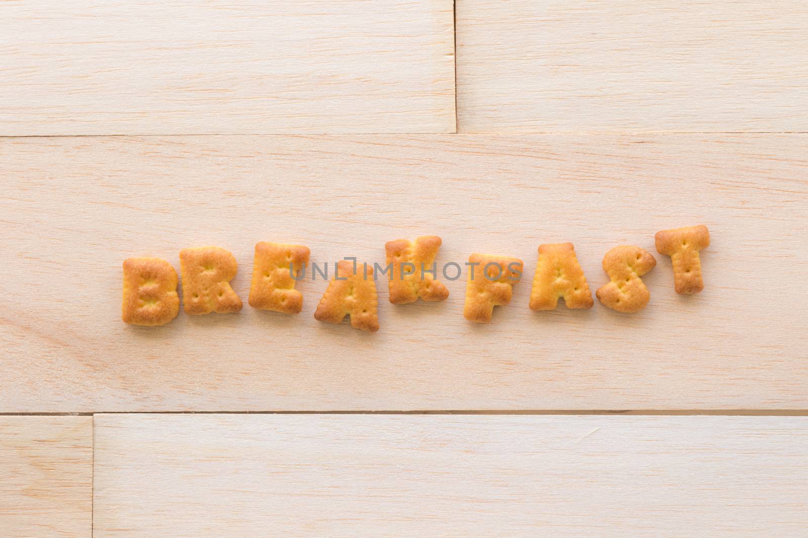 Top view of the capital letters word BREAKFAST. Alphabet cookie biscuits putting on piece of wood background.
