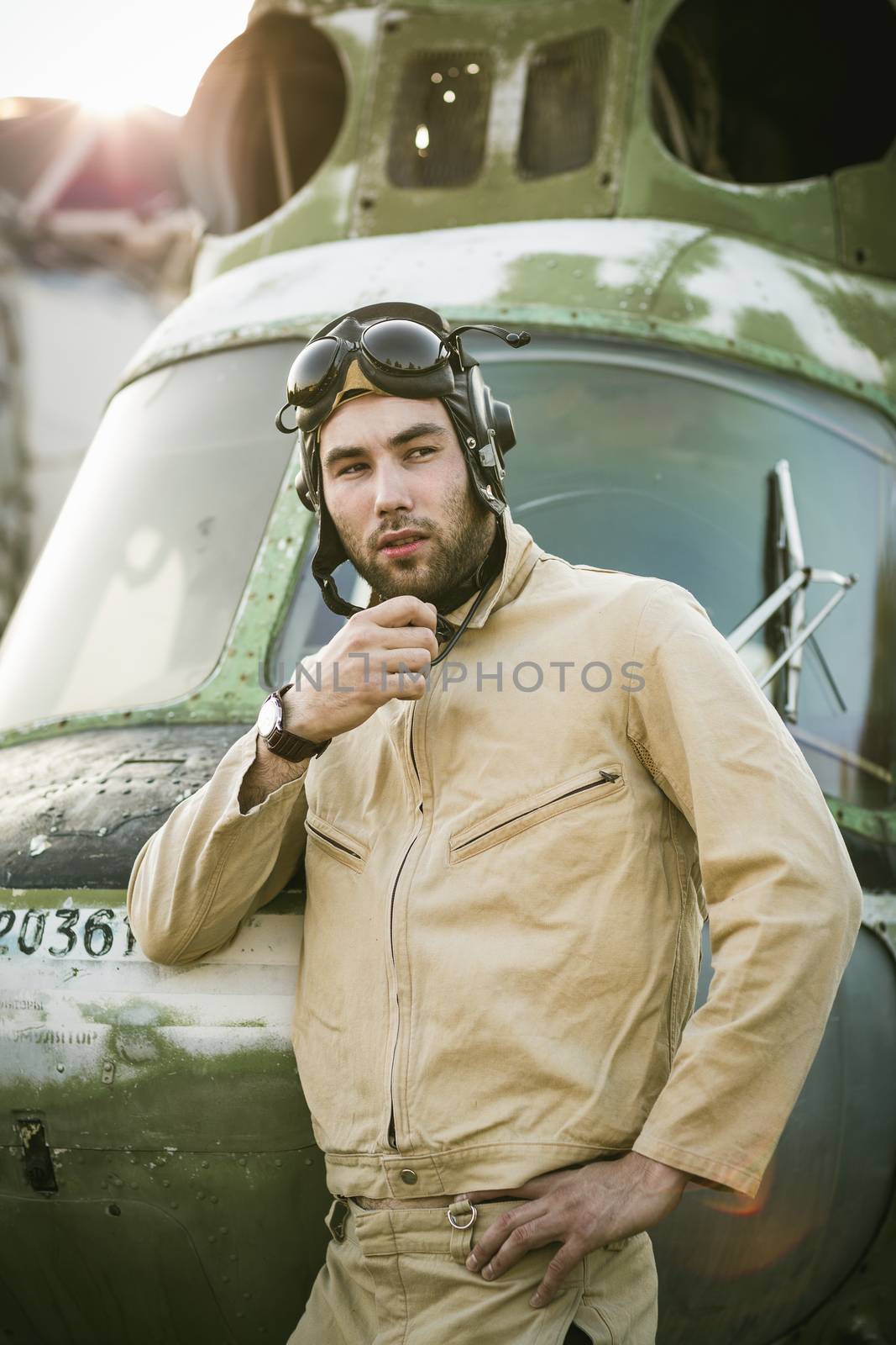 Young serious pilot posing near the helicopter
