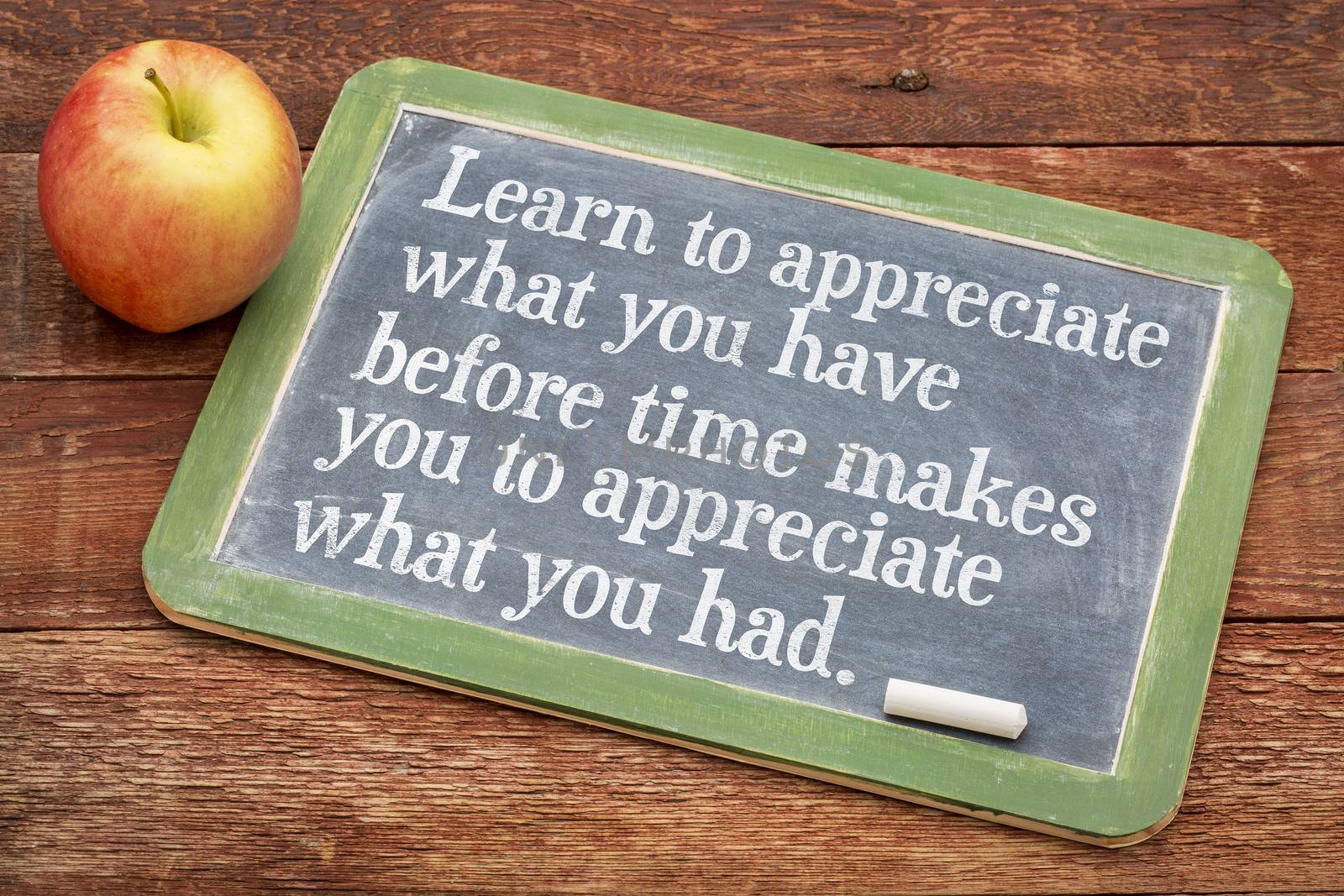 Learn to appreciate what you have before time makes you appreciate what you had - inspirational phrase on a slate blackboard against red barn wood