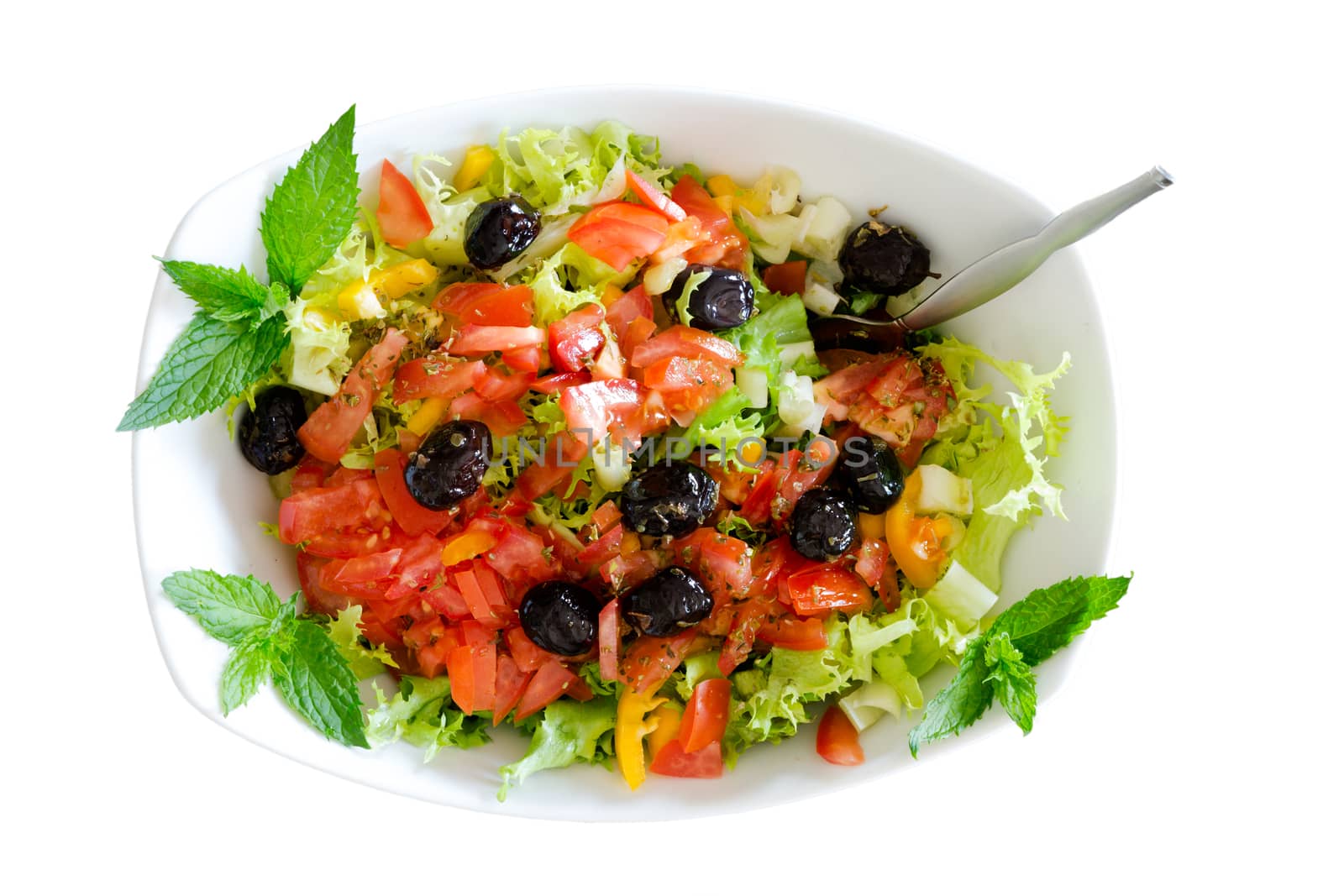 Isolated fresh plain salad garnished with sprigs of mint containing lettuce, tomato, sweet peppers and black olives served in a bowl with a fork