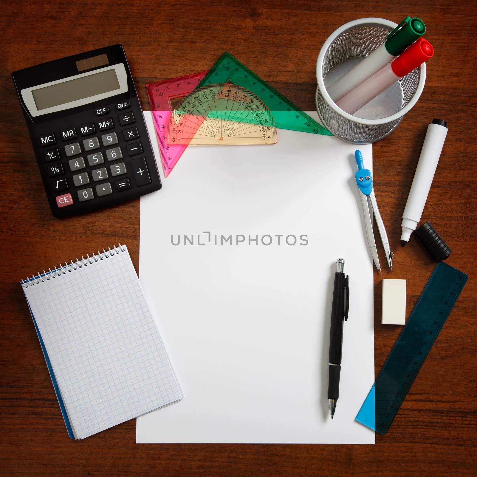 Desk with sheet of paper and stationery objects seen from above