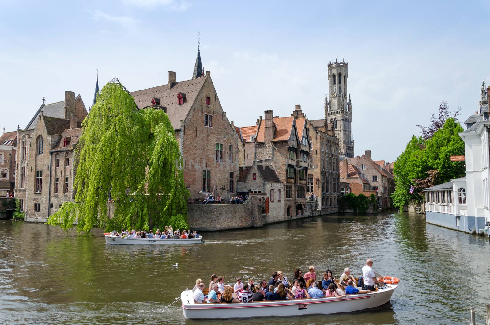 Bruges, Belgium - May 11, 2015: Tourist visit Rozenhoedkaai (The Quai of the Rosary) in Bruges, Belgium. One of Bruges most picturesque locations. With a view of the Bruges Belfry in the distance.