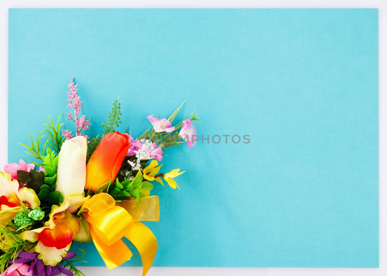 artificial flowers on blue background with place for label