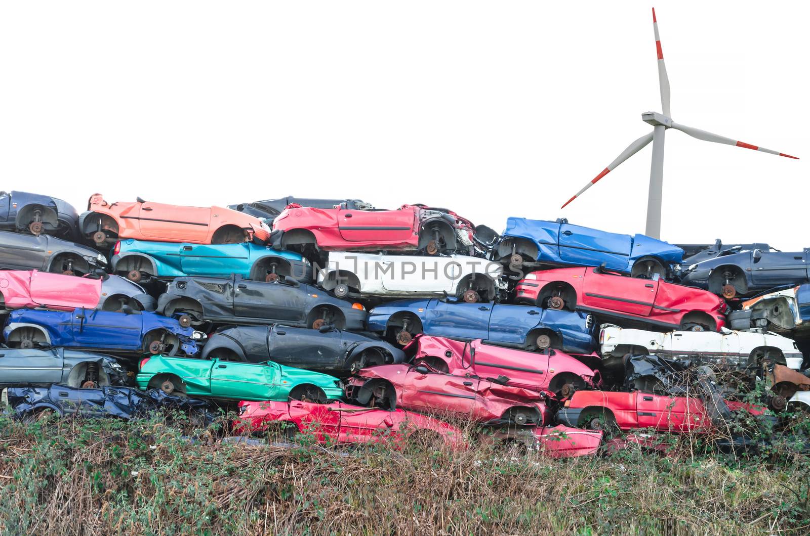 Scrap cars, scrap cars on a stack in the background a wind turbine for energy.