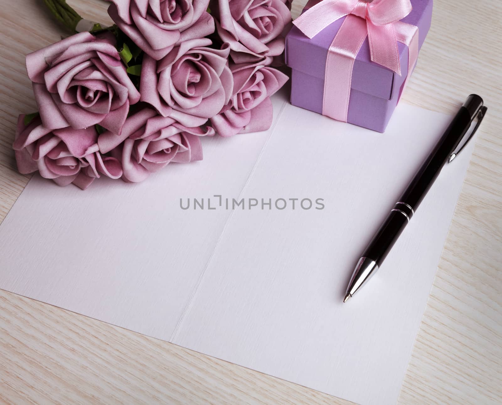 blank card with a pen, purple roses and purple gift box