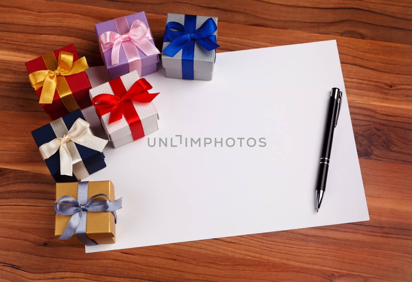 blank card with a pen and colored gift boxes top view