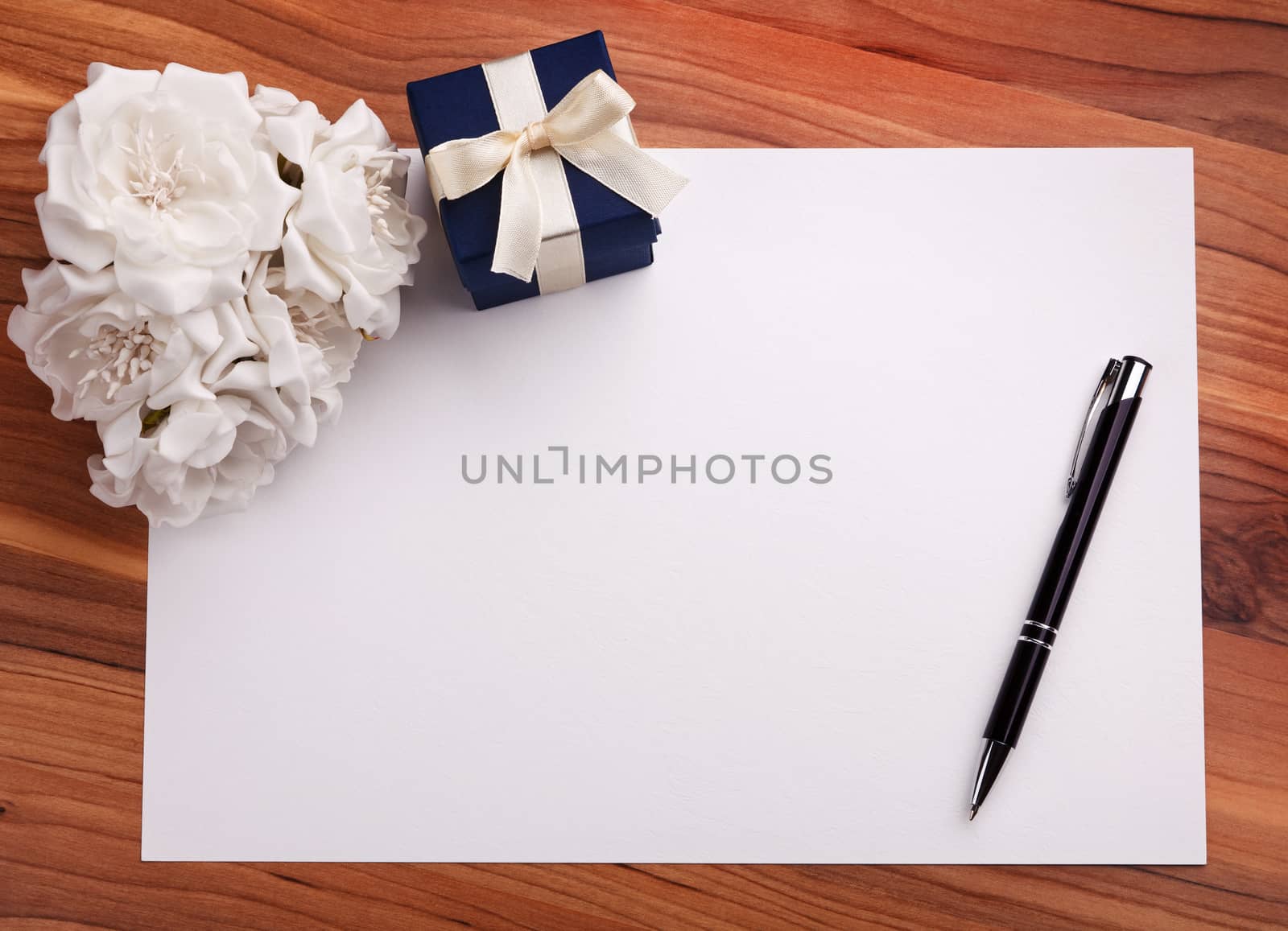 Greeting card with pen, white flowers and a blue gift box