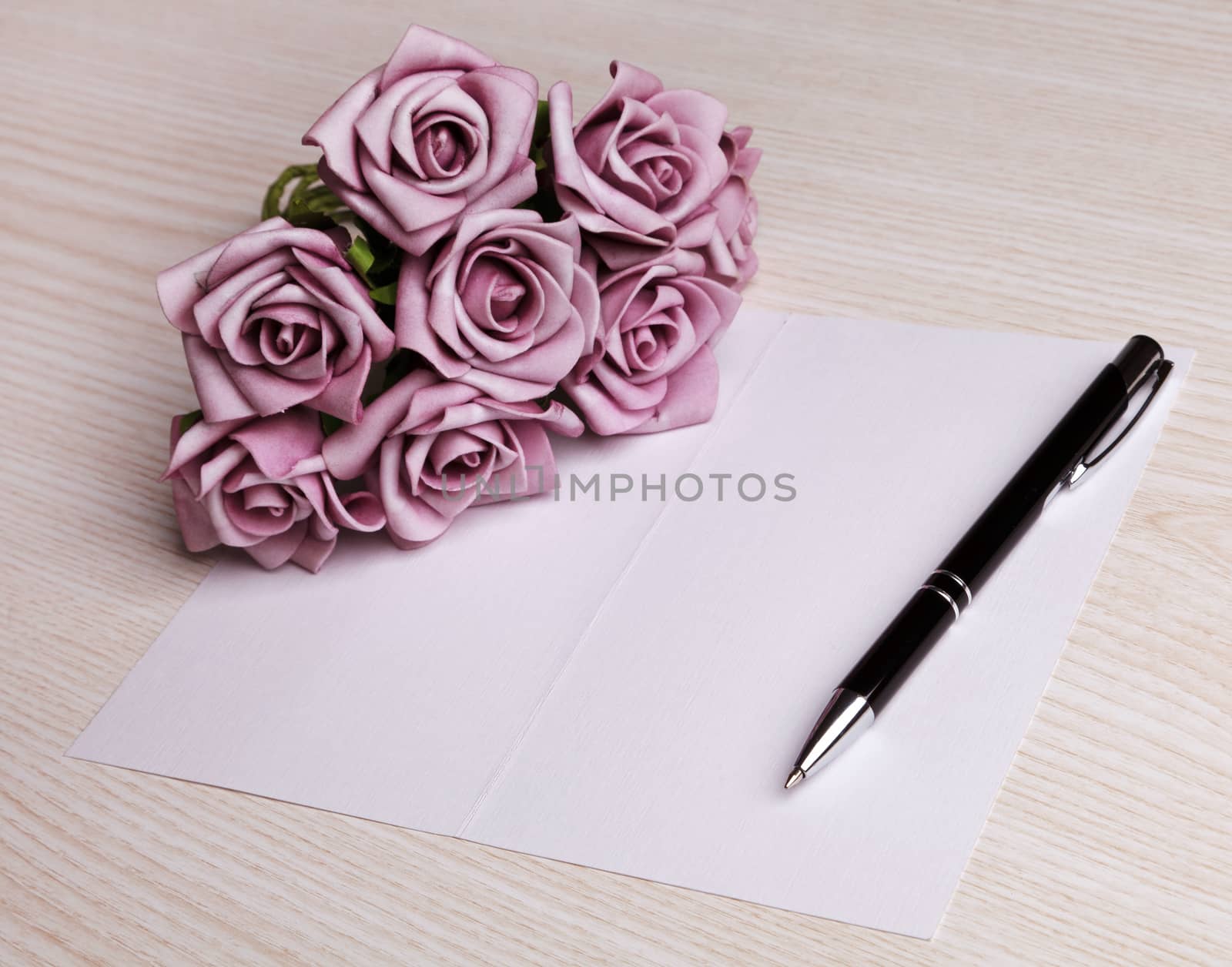 blank card with a pen and  purple roses 