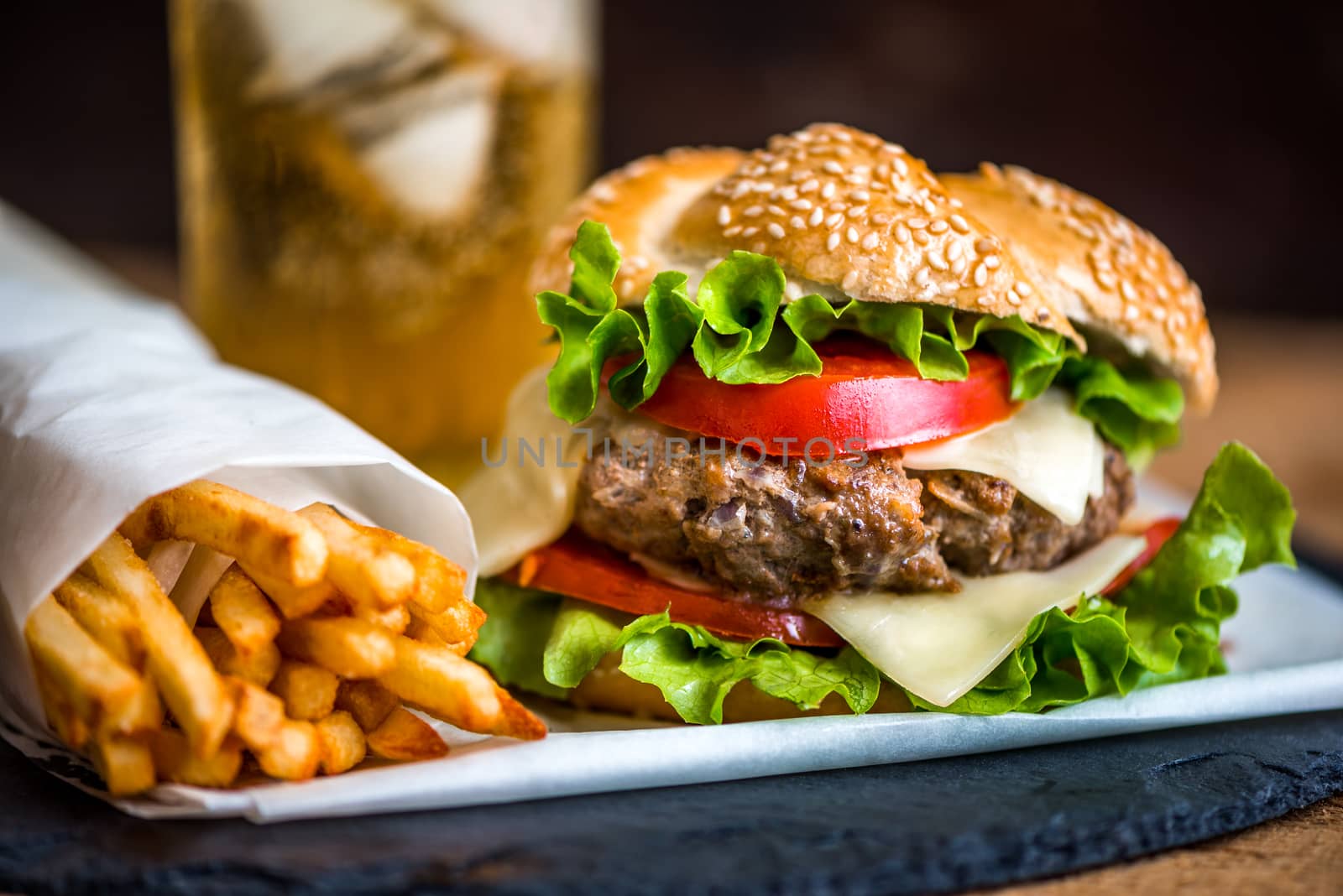 Closeup of Homemade Hamburger with Fresh Vegetables and Drink with Ice in Background