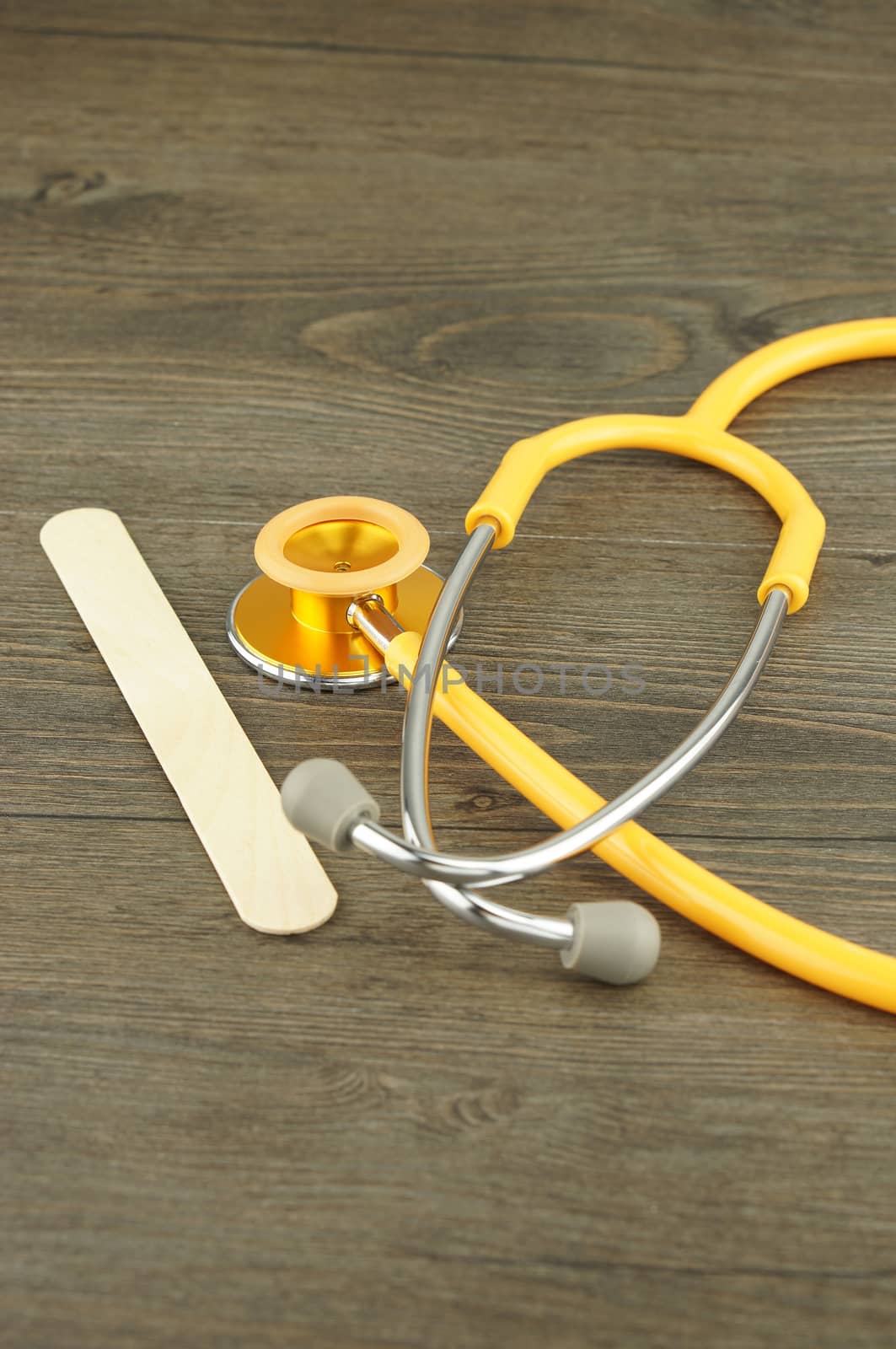 Wooden tongue depressor and stethoscope placed on table in examination room.                              