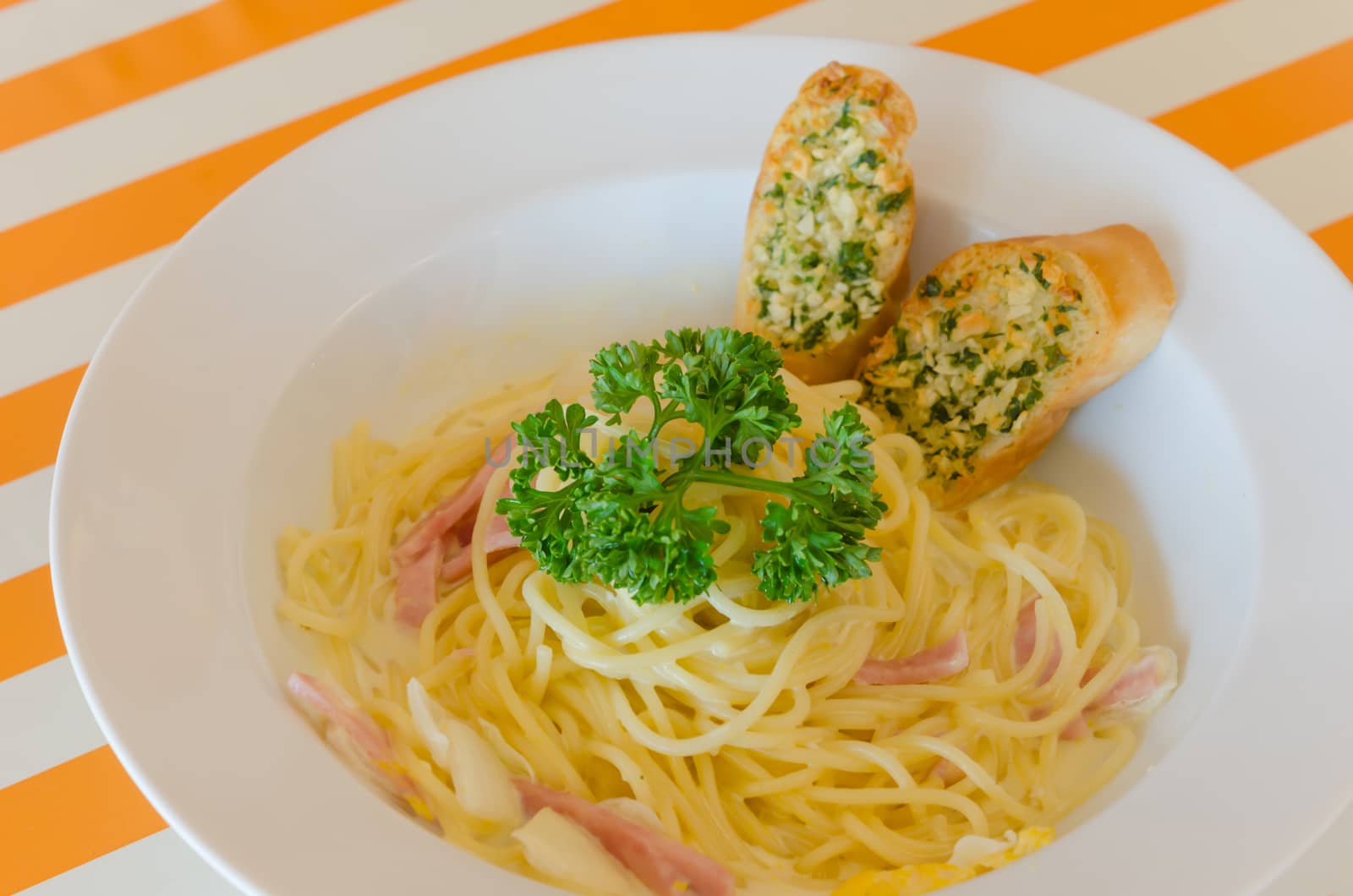 Spaghetti Carbonara with bacon and garlic bread on dish