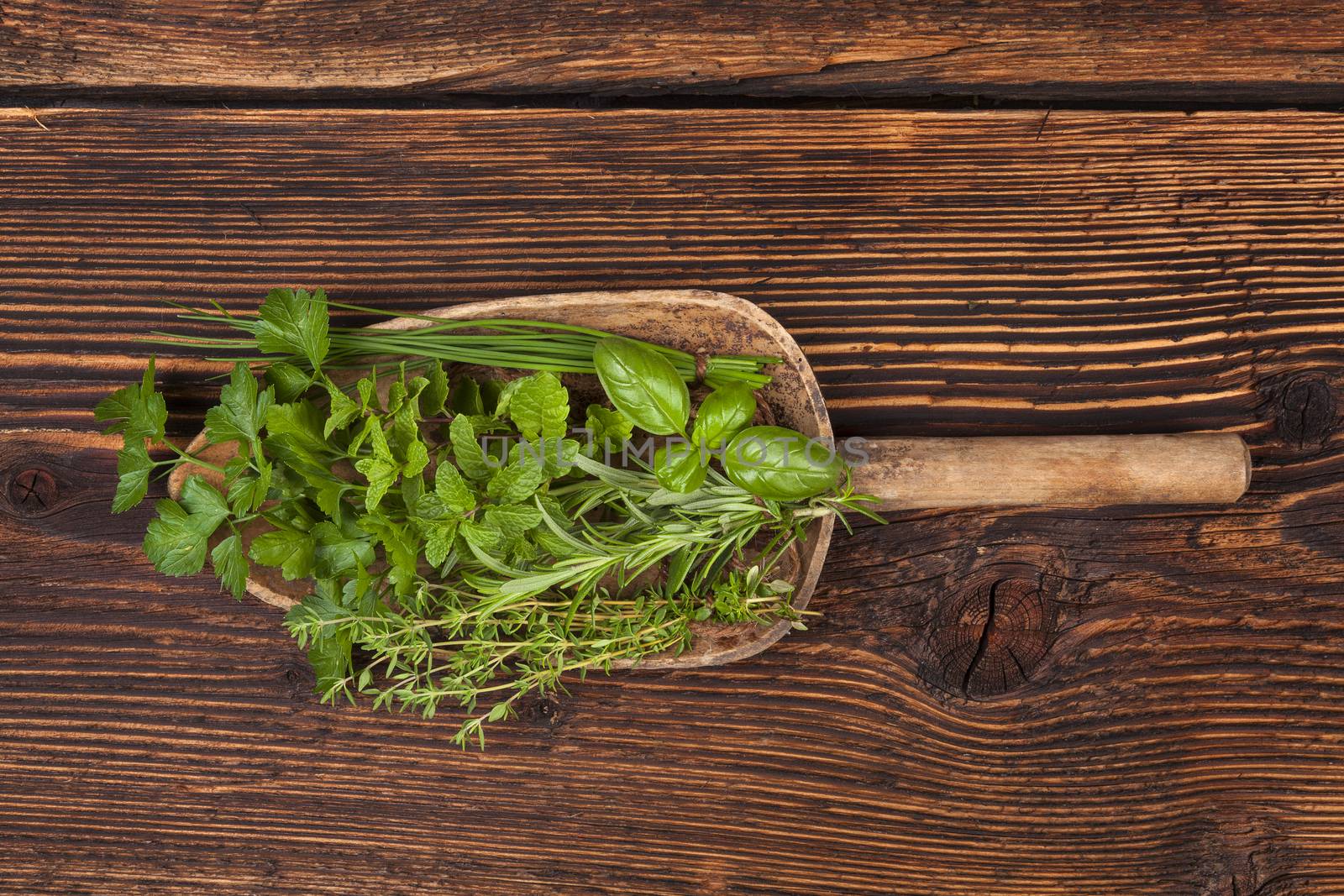 Various aromatic culinary herbs. Thyme, marjoram, basil, mint, chives and parsley herbs on wooden spoon on old brown wooden background. Rustic, vintage, natural, country style images.