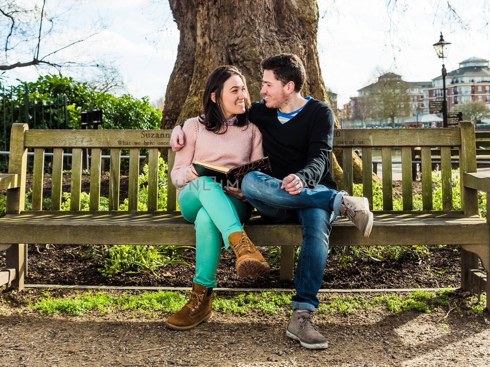 Couple in Love Hugging and Dating Sitting on a Bench in a Park Looking at Each Other