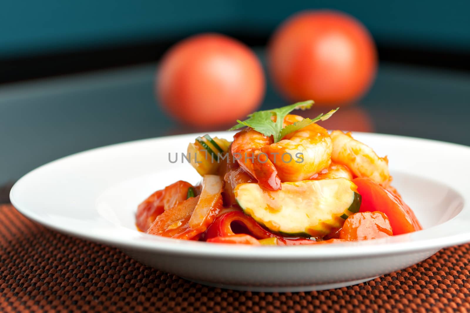 Thai style sweet and sour shrimp dish presented beautifully on a round white plate.