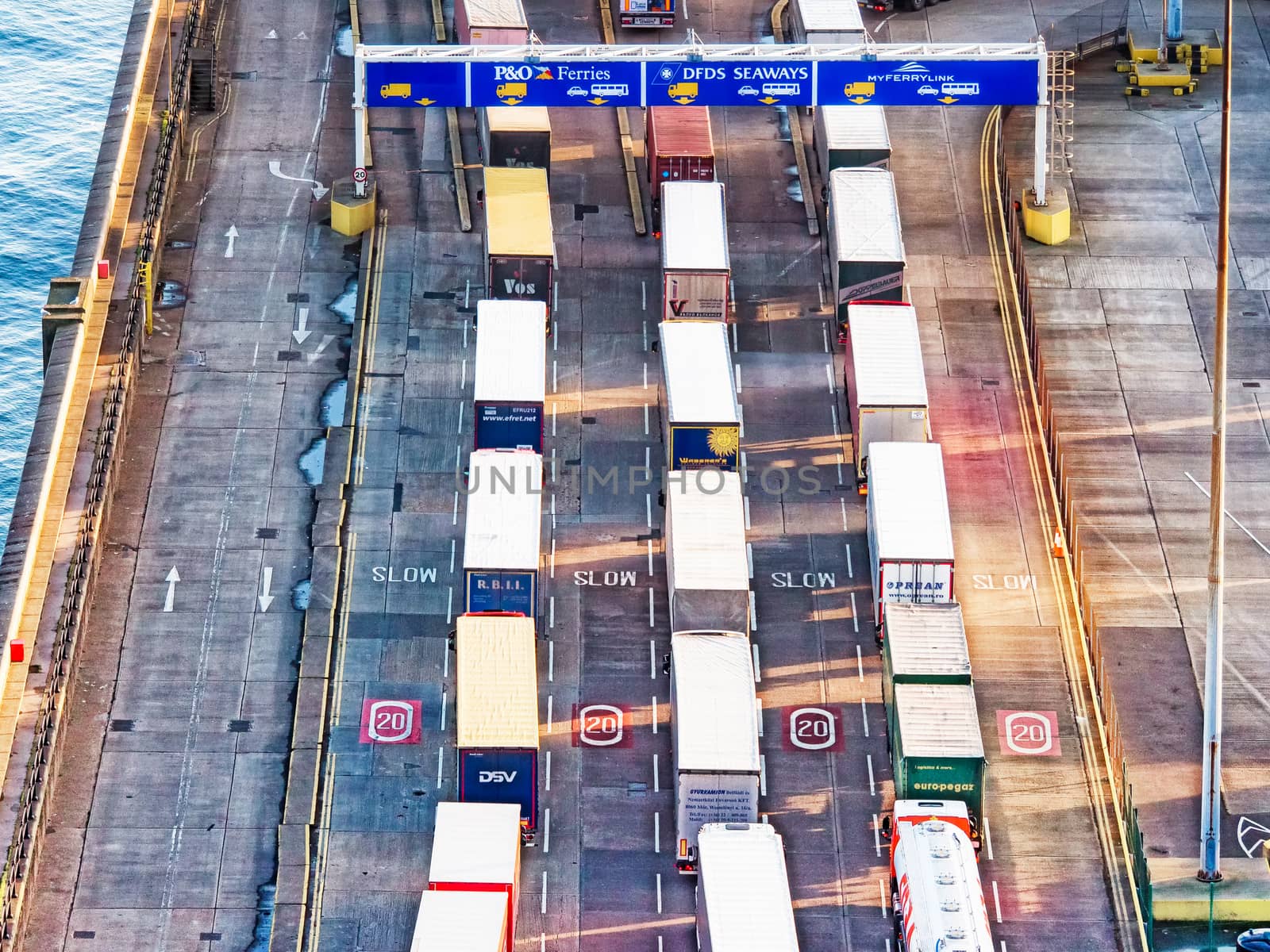 Line of trucks in sea port with many containers waiting to be shipped