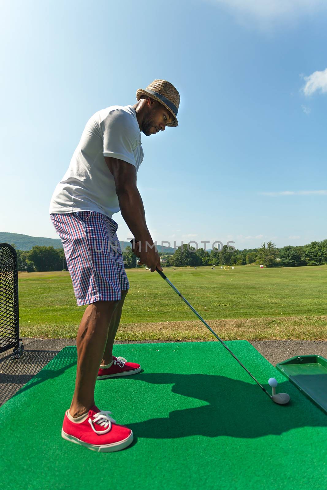 Golfer Teeing Up at the Driving Range by graficallyminded