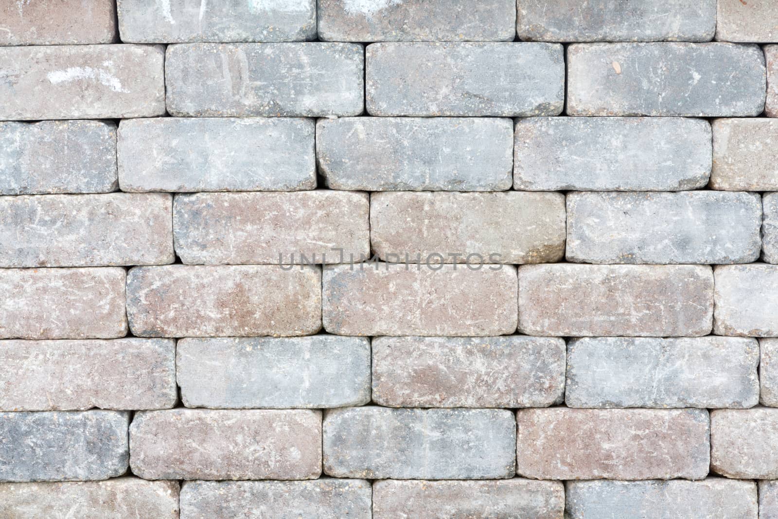 Background texture of a tumbled brick wall with aged variegated rectangular bricks with worn edges in a mortarless decorative construction