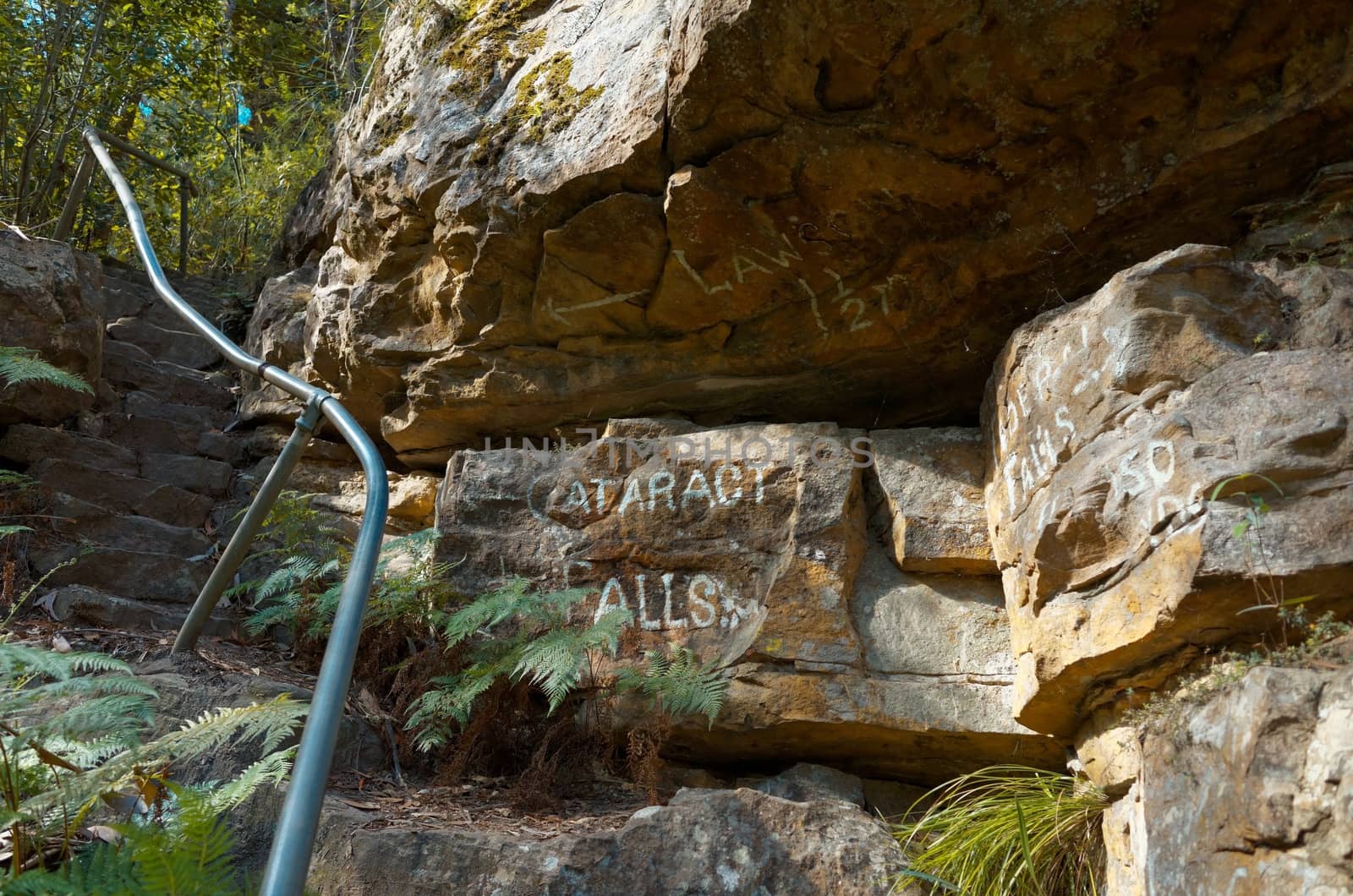 Stones steps on the side of a rock with painted direction signs in the Blue Mountains of Australia.