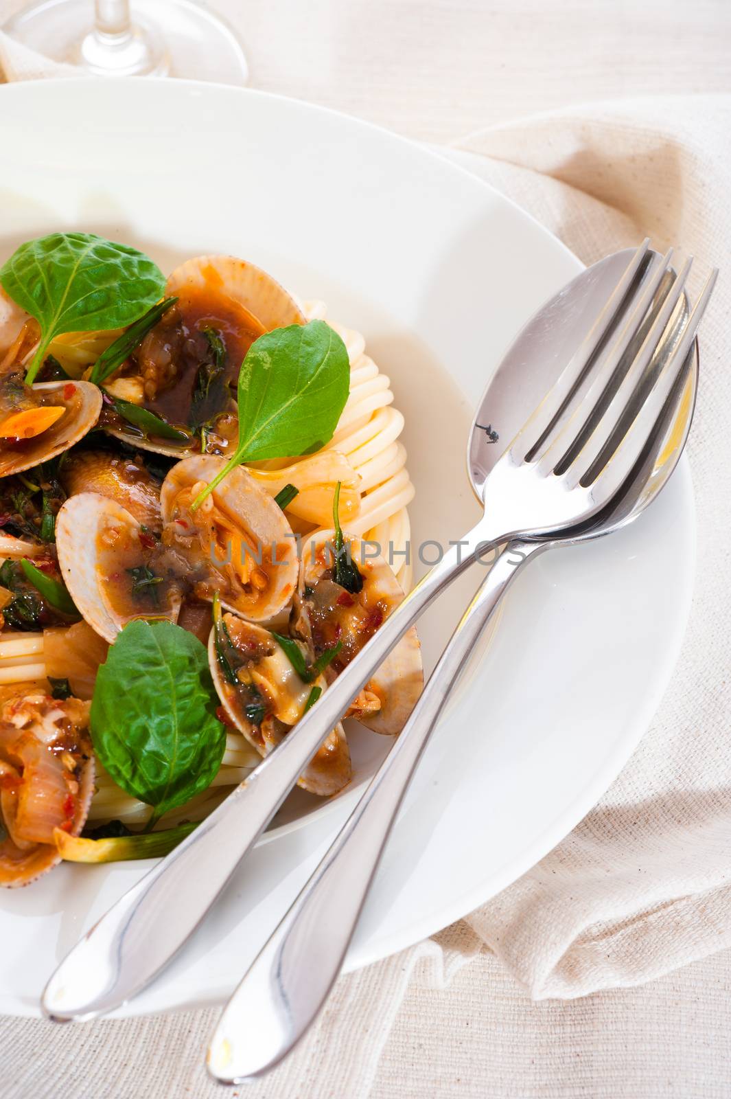 A white plate with delicious spaghetti shellfish and green basil.