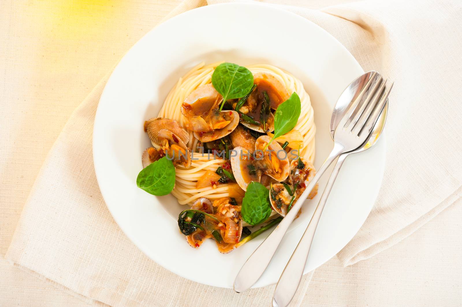 A white plate with delicious spaghetti shellfish and green basil.