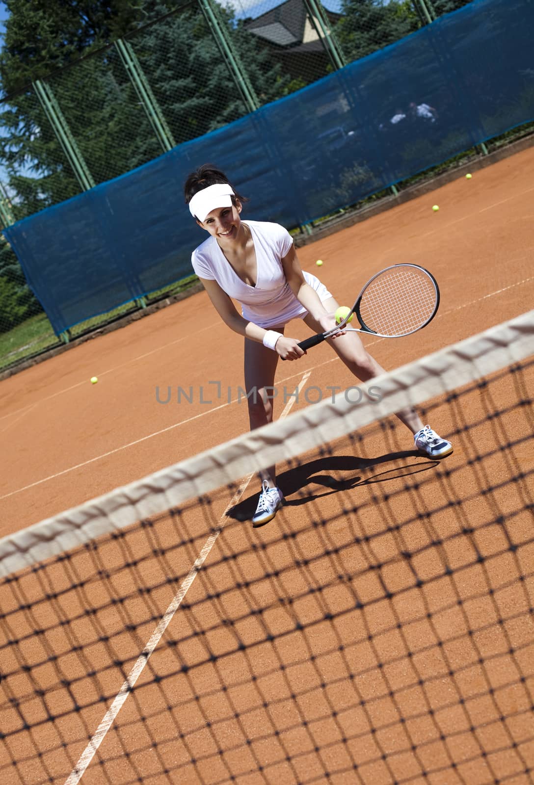 Girl playing tennis on the court by JanPietruszka