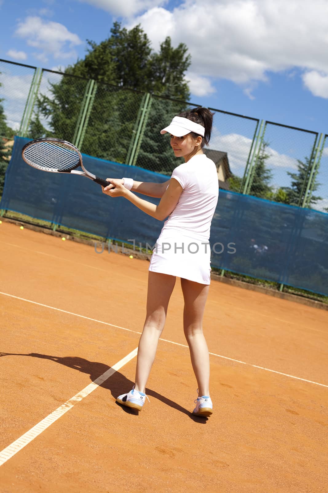 Girl playing tennis on the court by JanPietruszka