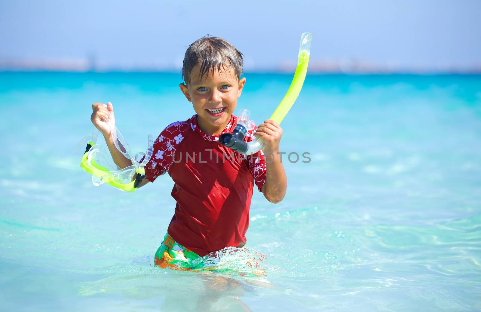 Portrait of happy cute boy with snorkeling mask ready to dive in the sea