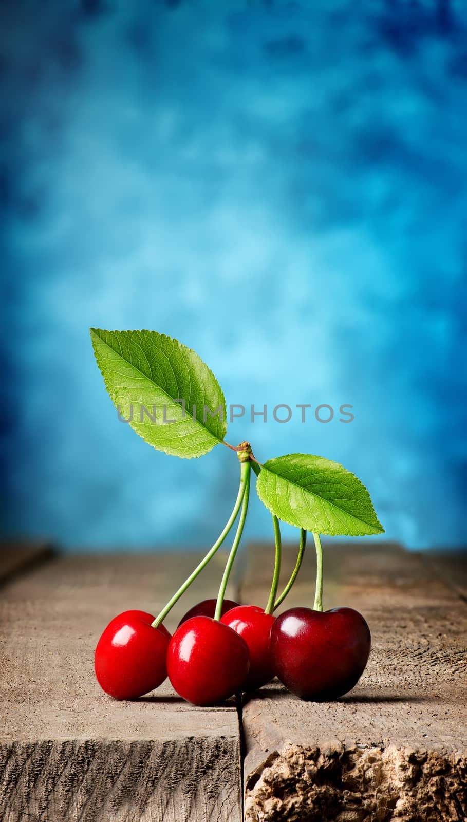 Cherries on wooden table on a blue background