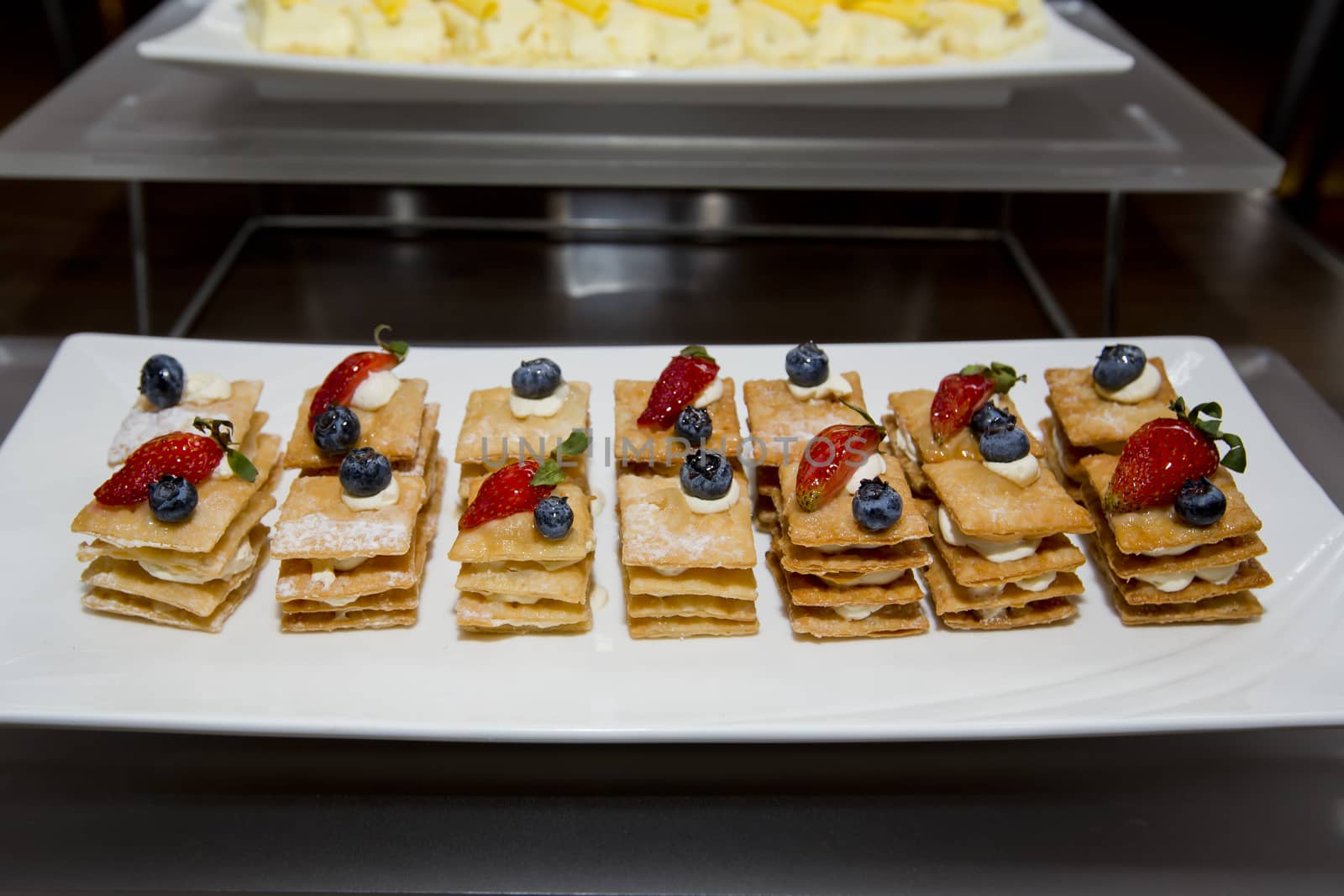 Stack of crispy pancake with banana slice topping of strawberry, blueberry and sugar