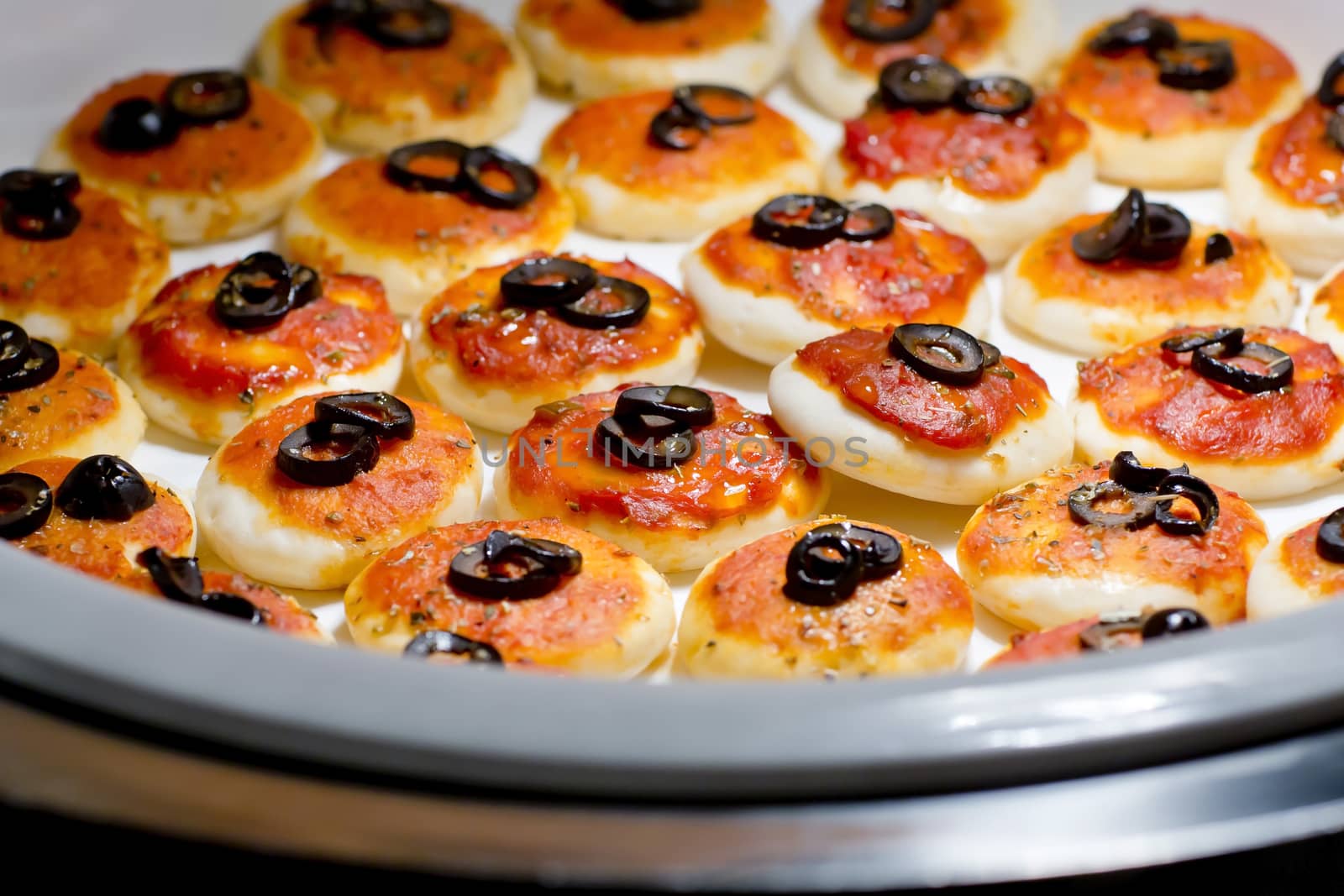round meat pies with topping black olive sliced on buffet line