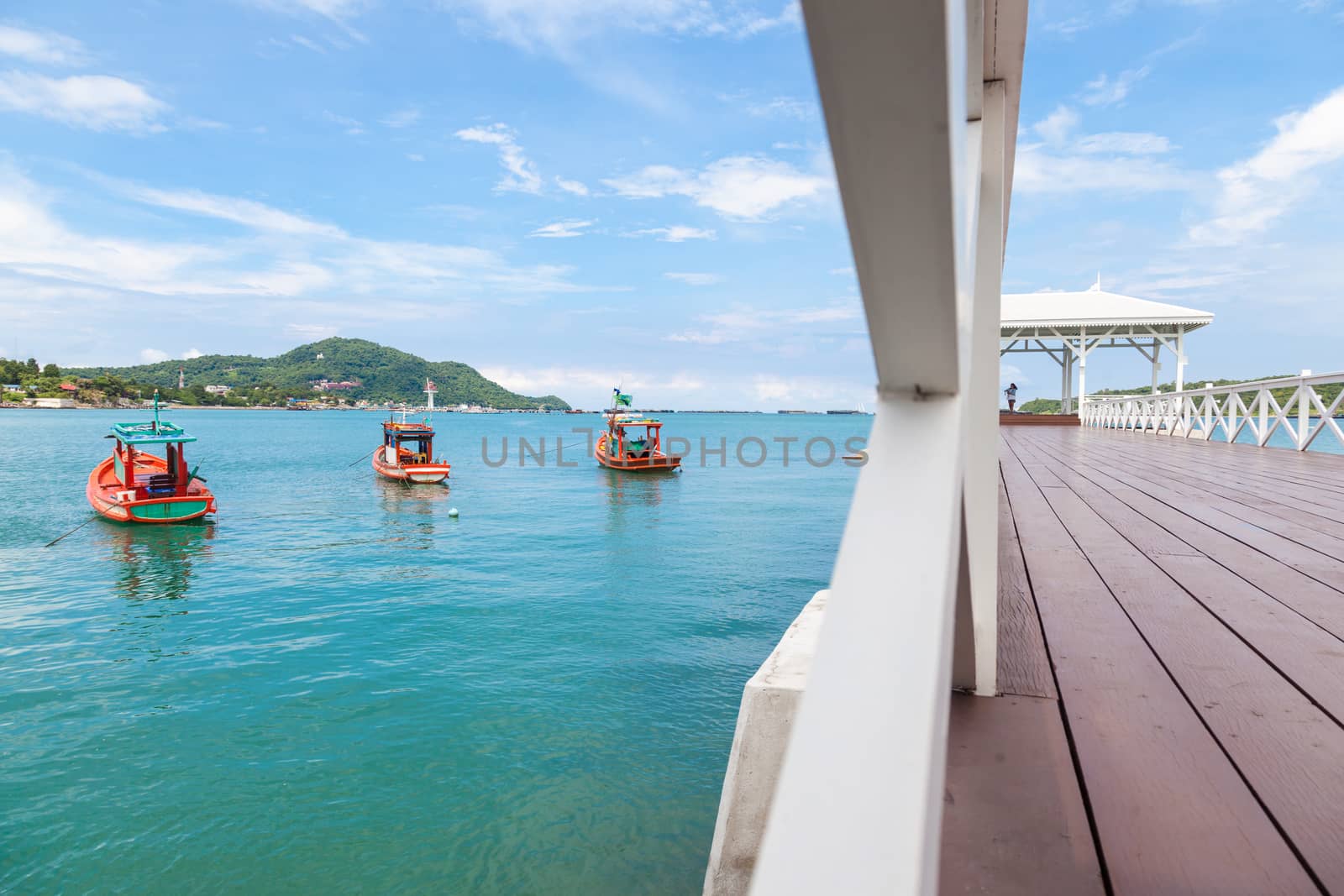 wooden bridge that stretches to the sea. A fishing boat moored near the bridge.