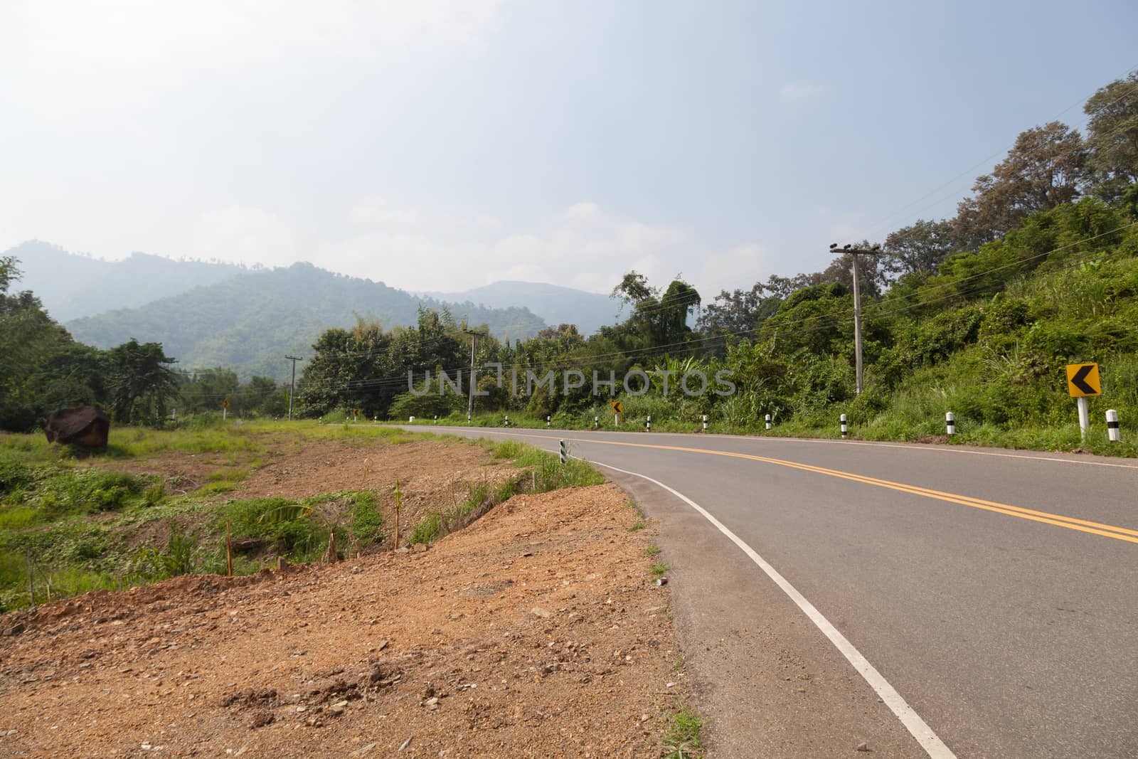 The road on the mountains. The road cuts through the mountains. The trees along the road