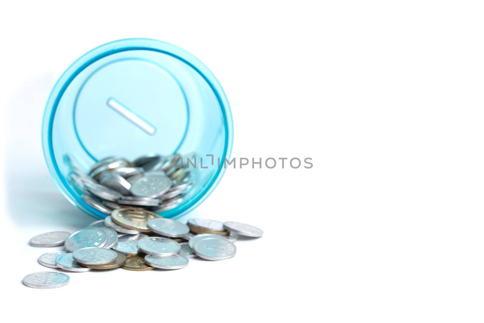 Many Japanese Yen coins pouring out of a blue bank onto a white background.