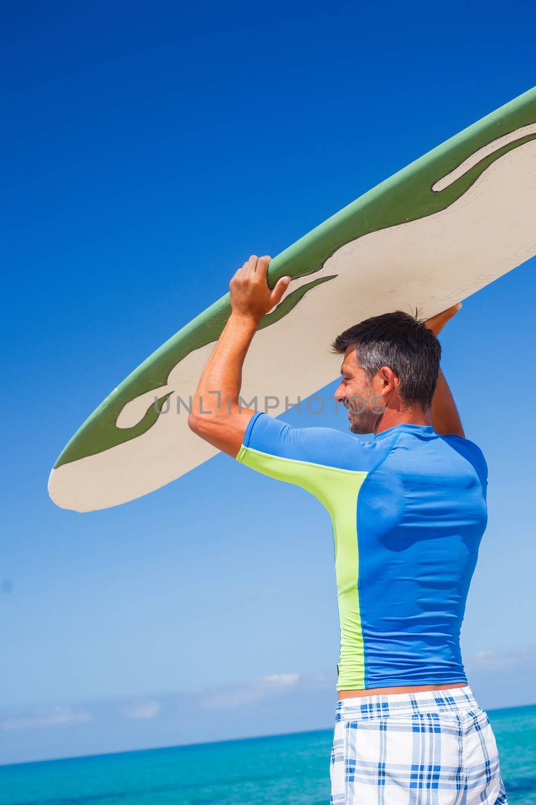 Strong young surf man at the beach with a surfboard.