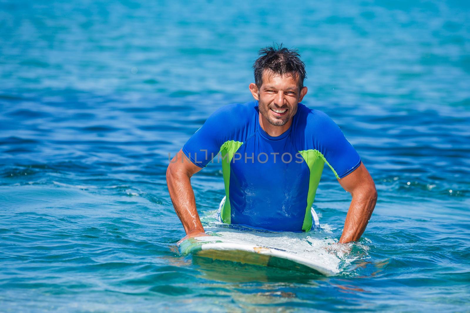 Strong young surf man at the beach with a surfboard.