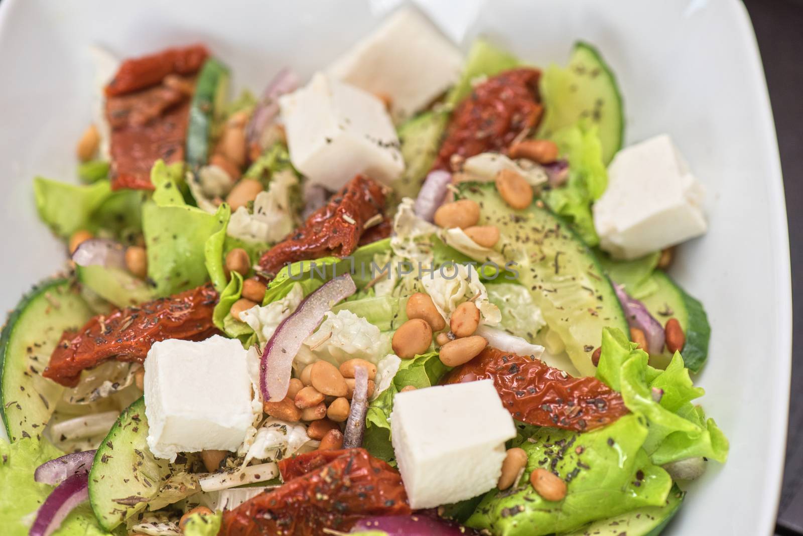 Salad feta cheese lettuce sausage cucumbers and pine nuts