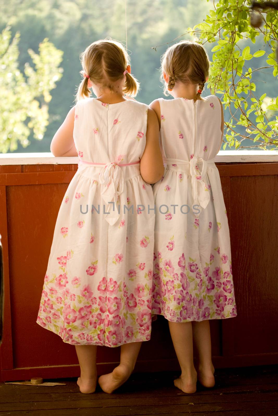 Twin girls on porch in summer dresses by kavring