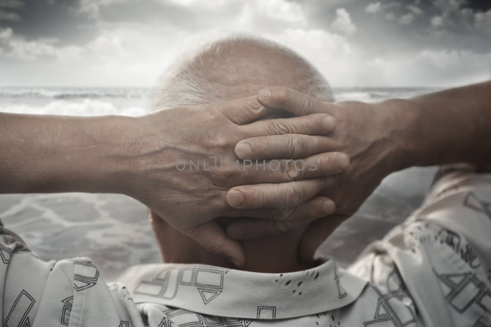 Senior man with hands behind his head looking at the sea