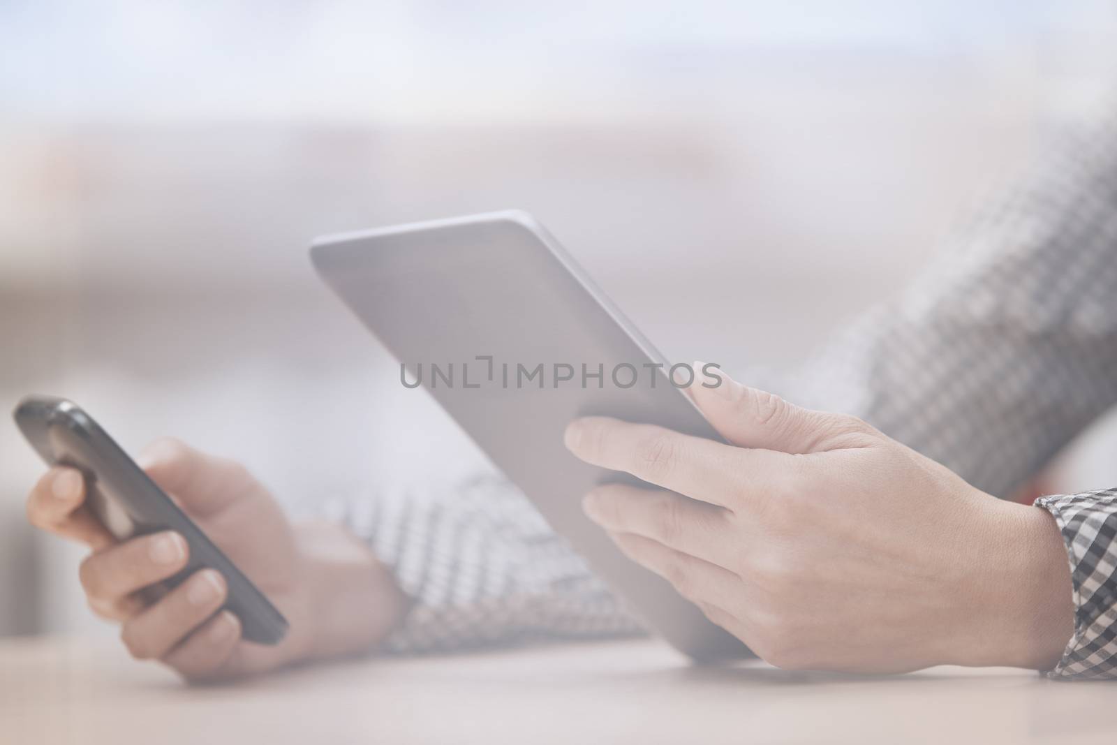 Businesswoman at office working with digital tablet and smartphone beinhd the window