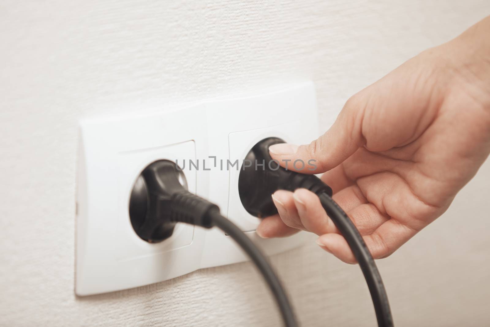 Woman pluging cable to the electric outlet