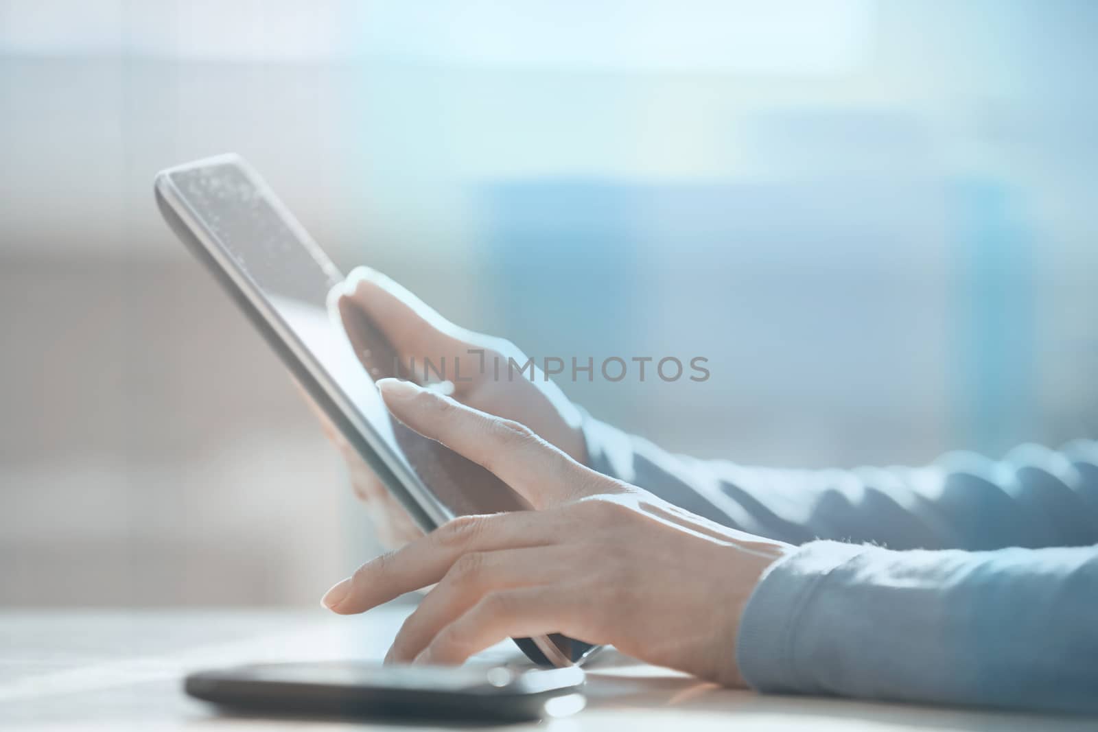 Hands of woman working with digital tablet behind the glass at office