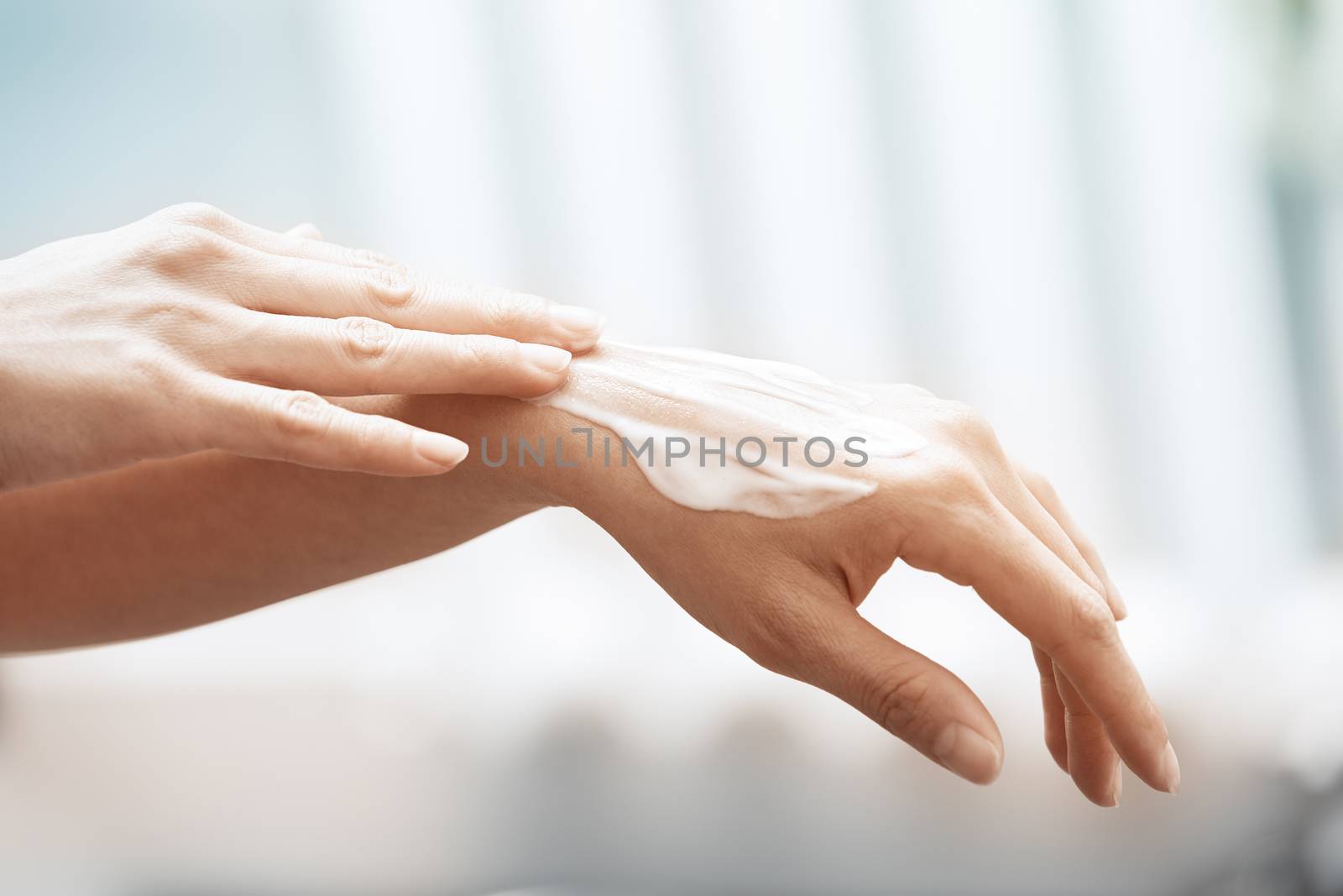 Woman applying moisturizing cream on hands