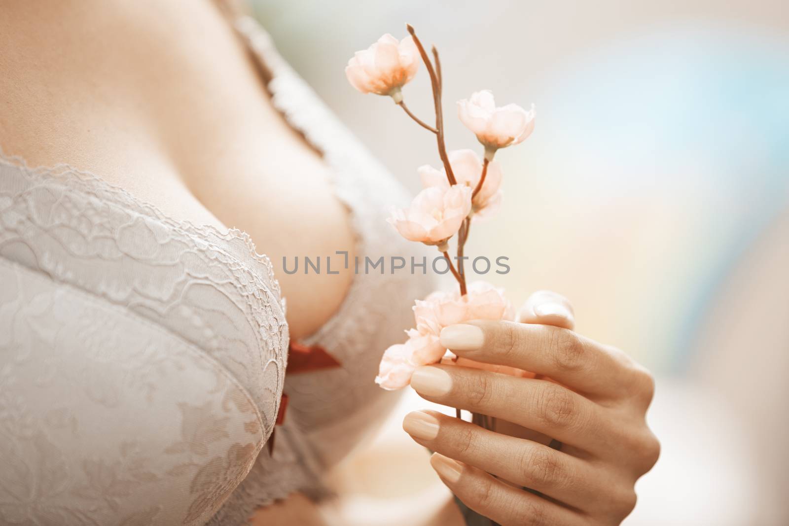 Woman in brassiere holding Sakura flower. Close-up horizontal photo