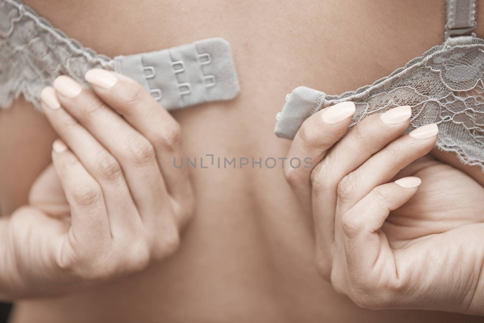 Woman undressing brassiere. Close-up rear view photo