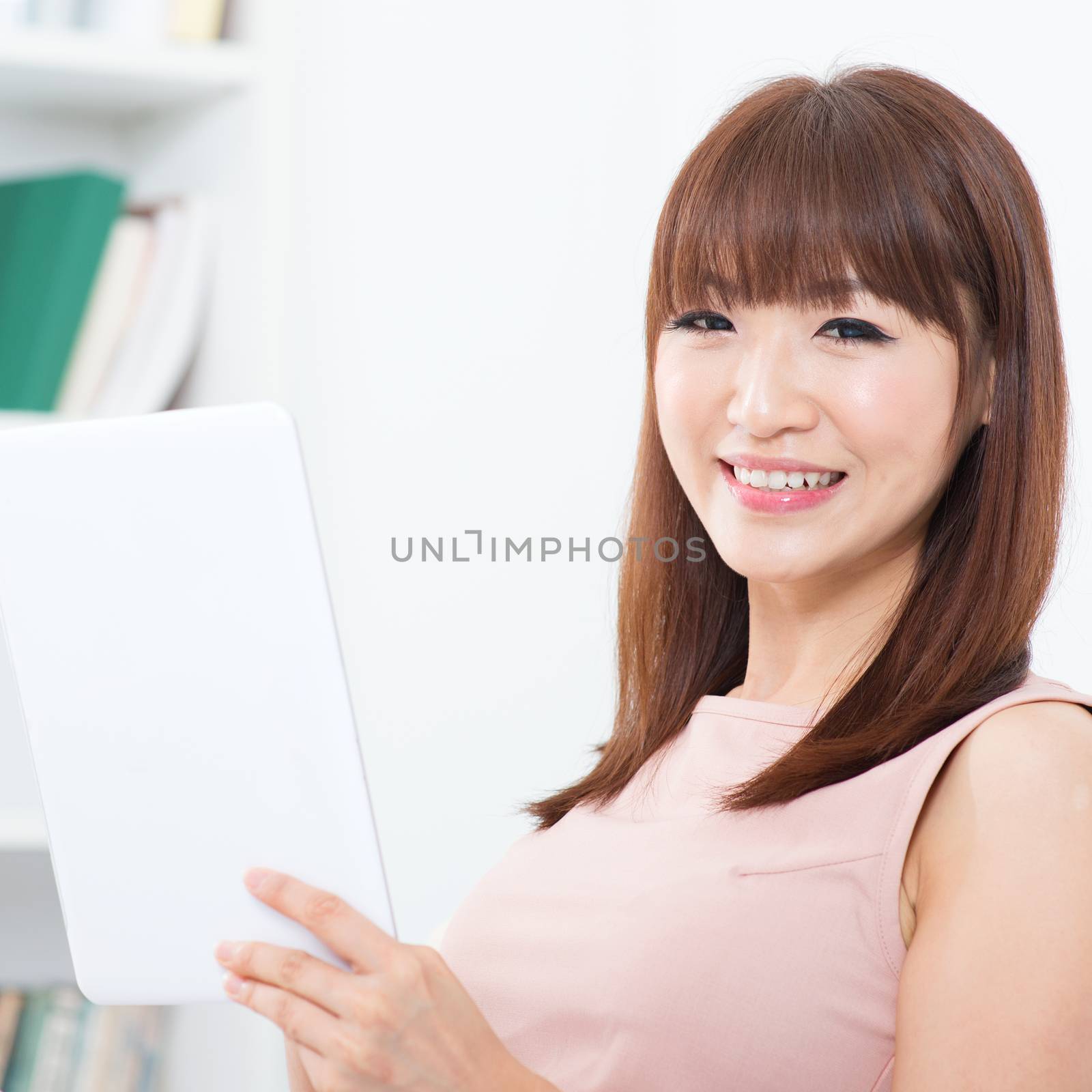 Portrait of attractive Asian girl using digital tab and smiling happily. Young woman indoors living lifestyle at home.