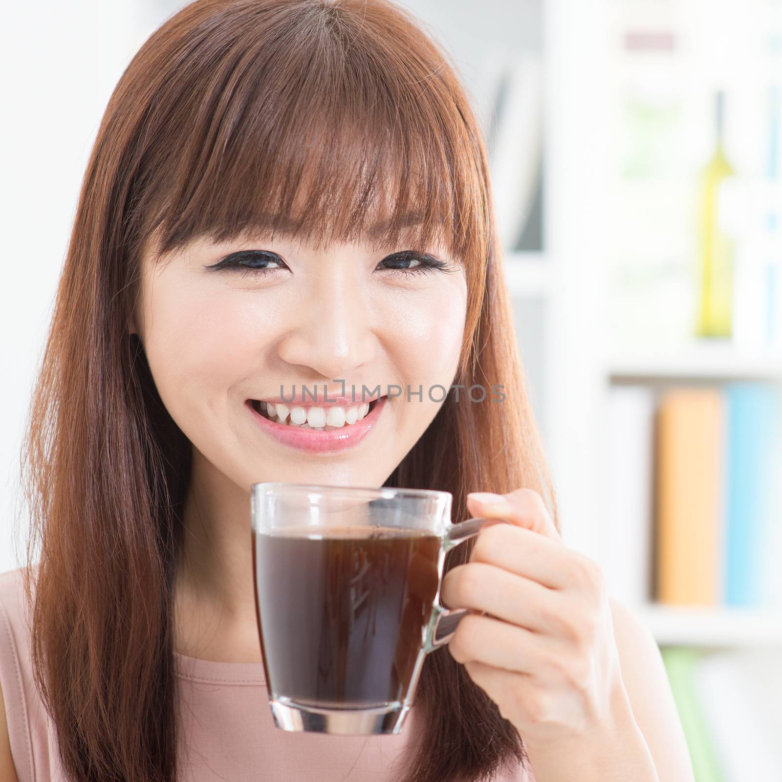 Portrait of happy Asian girl enjoying cup of hot coffee in the morning. Young woman indoors living lifestyle at home.