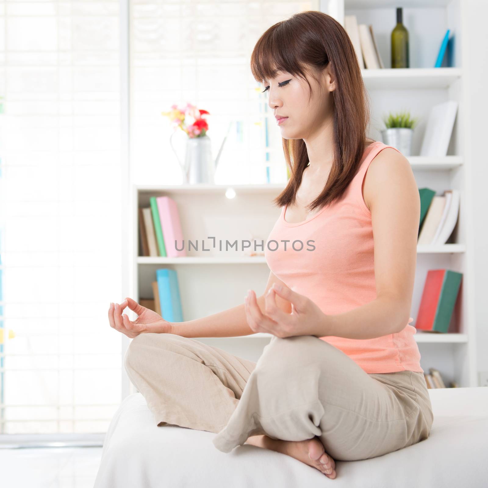 Portrait of calm Asian girl meditation in the morning. Young woman indoors living lifestyle at home.