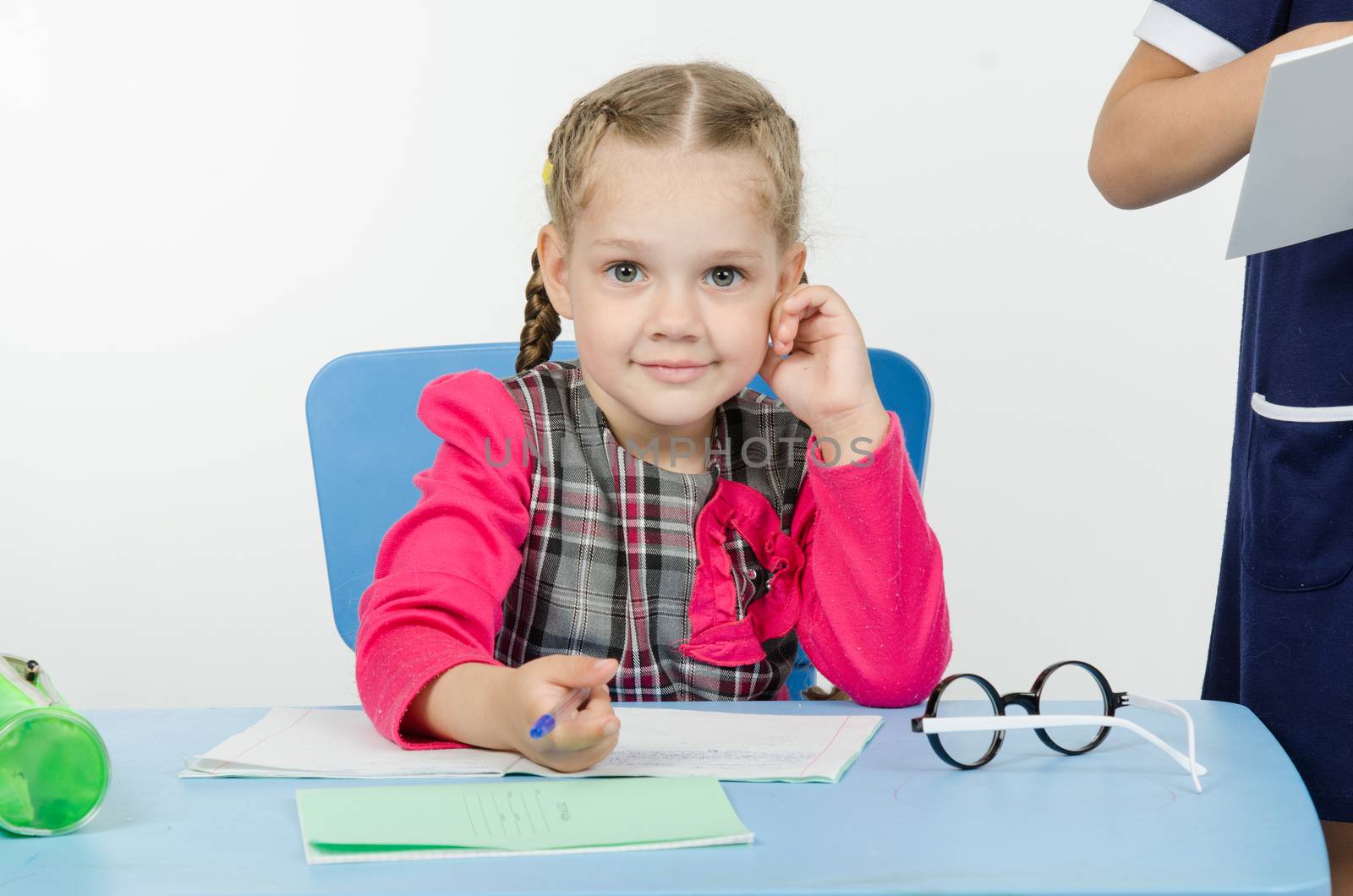 Girl sits at a table on which lay a notebook and writes them