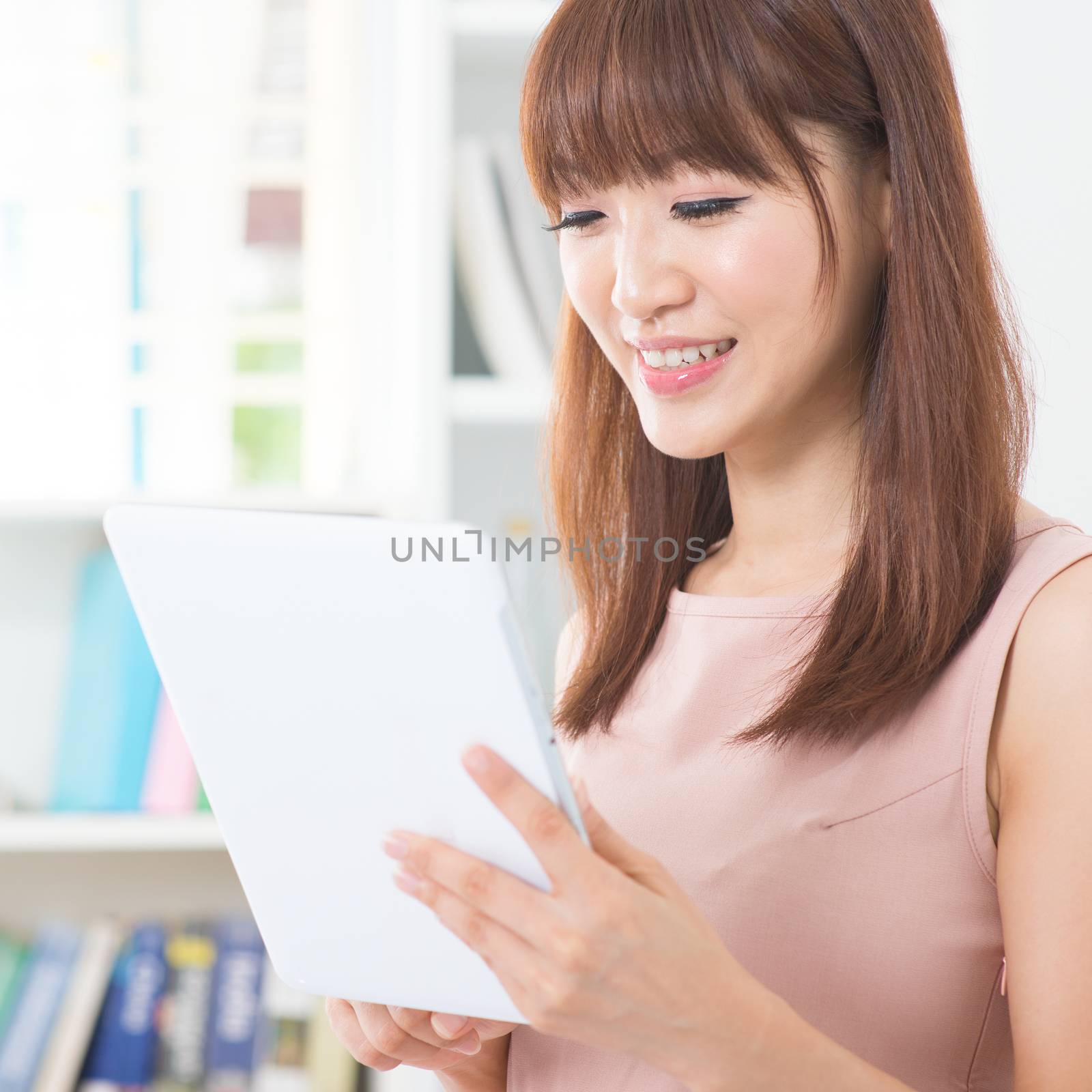 Portrait of attractive Asian girl using digital pc tablet. Young woman indoors living lifestyle at home.