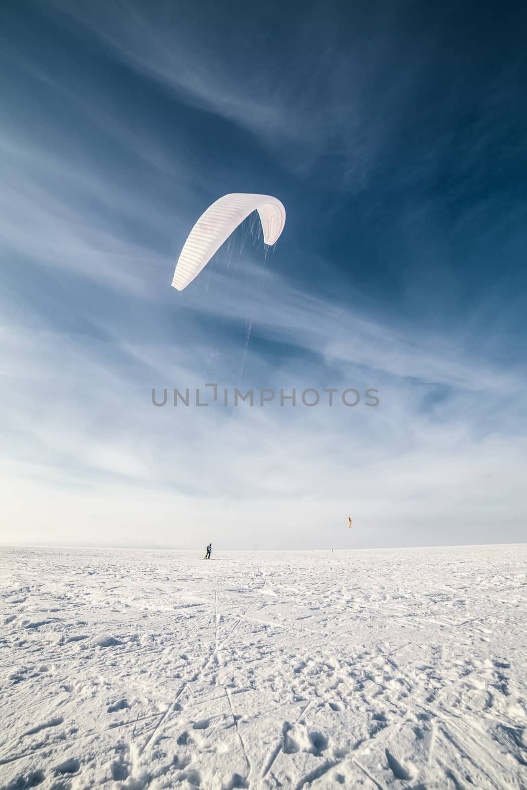 Kite surfer being pulled by his kite across the snow